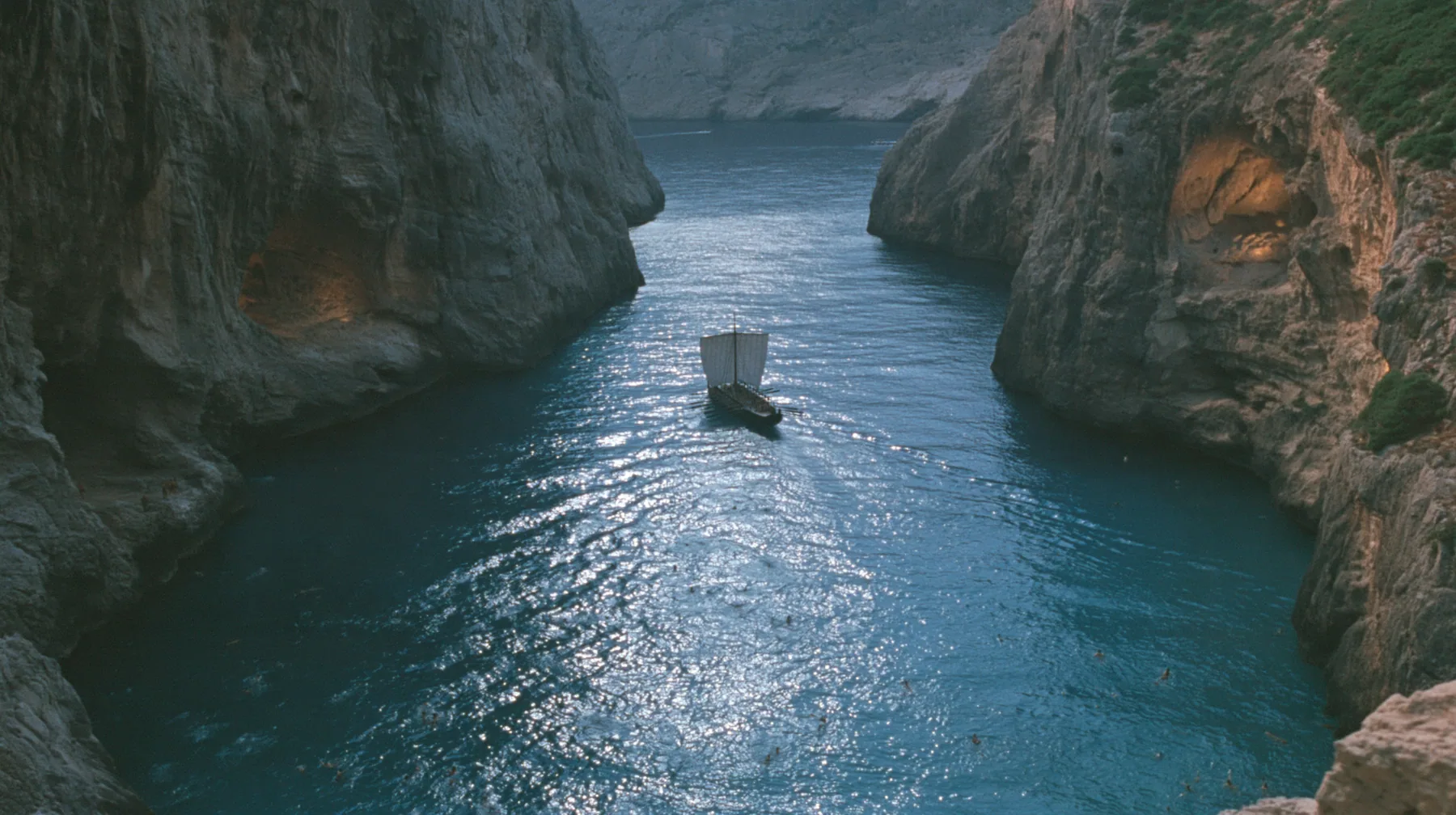 high aerial of the dark water of a narrow sea strait between two cliffs of lit alcoves, tiny swimmers far below drawn toward the cliffs, a long black ancient Greek galley with a single mast, a square sail and two…