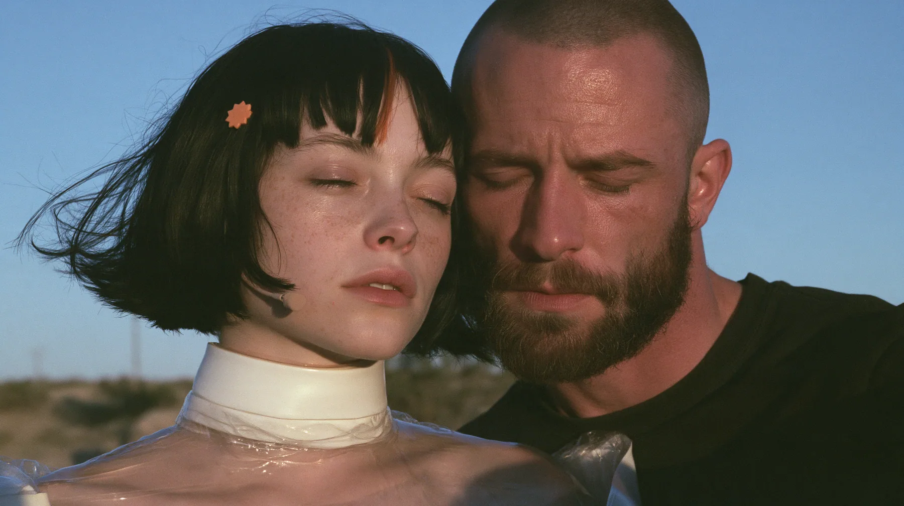 close-up of a Caucasian American woman in her mid-twenties with pale skin and light freckles, a glossy black blunt jaw-length bob with heavy straight bangs and one clay-orange streak through the bangs, a small flat…