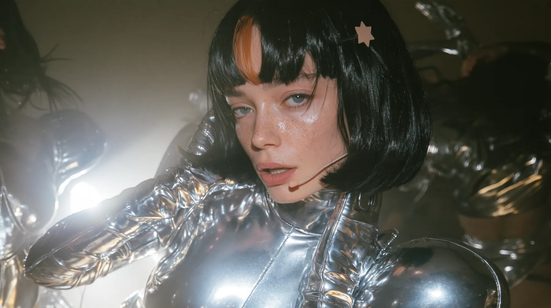 full-length shot of a Caucasian American woman in her mid-twenties with pale skin and light freckles, a glossy black blunt jaw-length bob with heavy straight bangs and one clay-orange streak through the bangs, a…