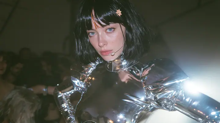 full-length shot of a Caucasian American woman in her mid-twenties with pale skin and light freckles, a glossy black blunt jaw-length bob with heavy straight bangs and one clay-orange streak through the bangs, a…