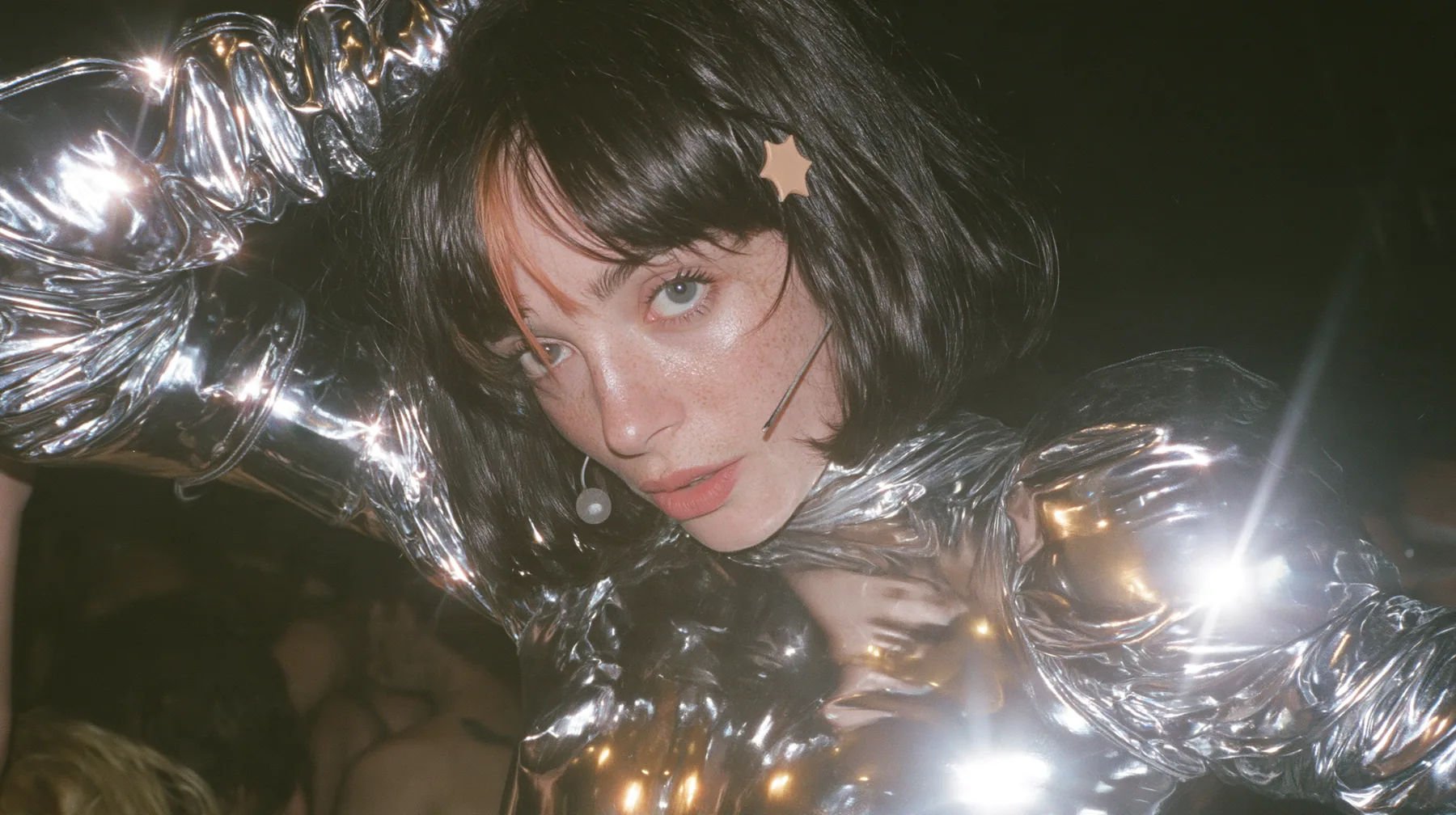 full-length shot of a Caucasian American woman in her mid-twenties with pale skin and light freckles, a glossy black blunt jaw-length bob with heavy straight bangs and one clay-orange streak through the bangs, a…