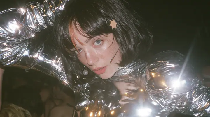 full-length shot of a Caucasian American woman in her mid-twenties with pale skin and light freckles, a glossy black blunt jaw-length bob with heavy straight bangs and one clay-orange streak through the bangs, a…