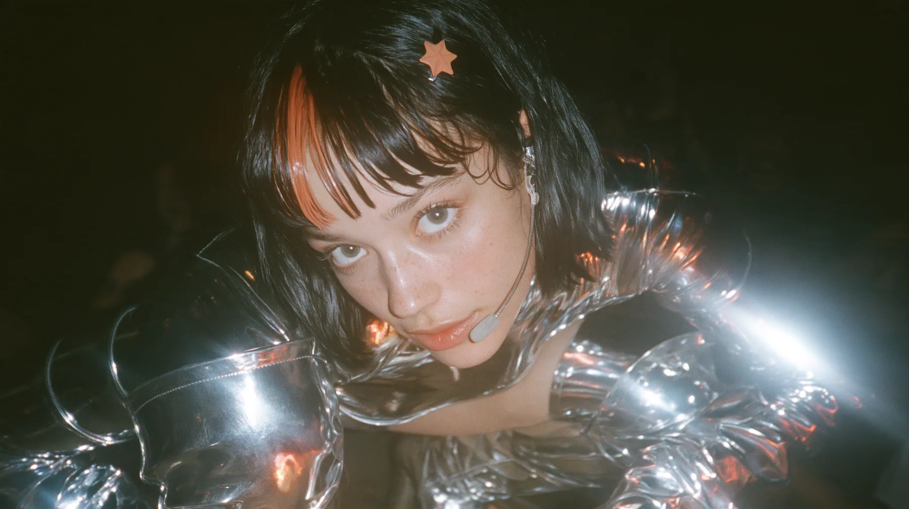 full-length shot of a Caucasian American woman in her mid-twenties with pale skin and light freckles, a glossy black blunt jaw-length bob with heavy straight bangs and one clay-orange streak through the bangs, a…