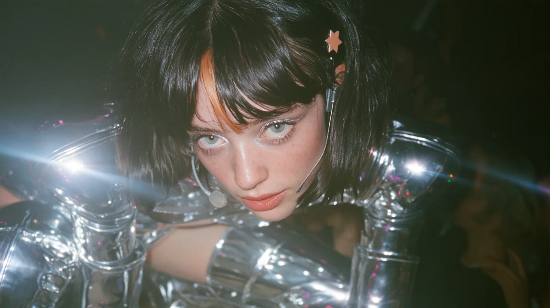 full-length shot of a Caucasian American woman in her mid-twenties with pale skin and light freckles, a glossy black blunt jaw-length bob with heavy straight bangs and one clay-orange streak through the bangs, a…