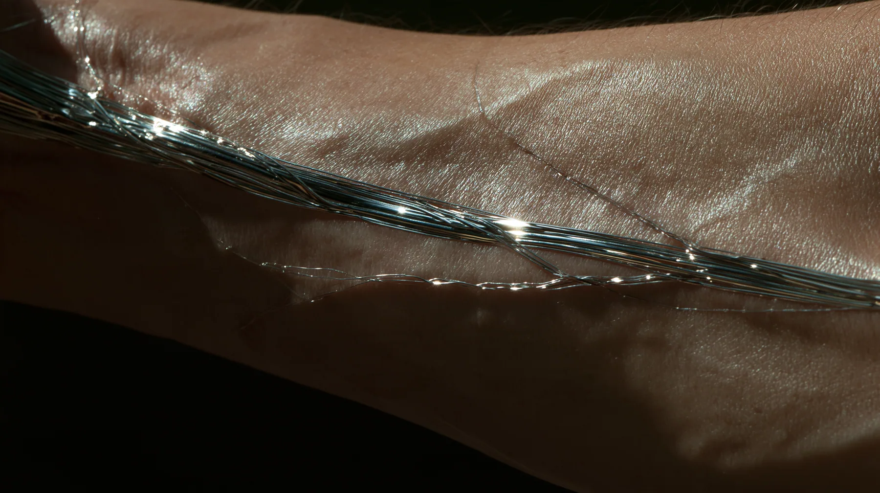 macro of a man's forearm with threads of liquid chrome showing through the veins under the skin, macro product photograph, hard rim light, razor-thin focus, no text, no letters, no logos
