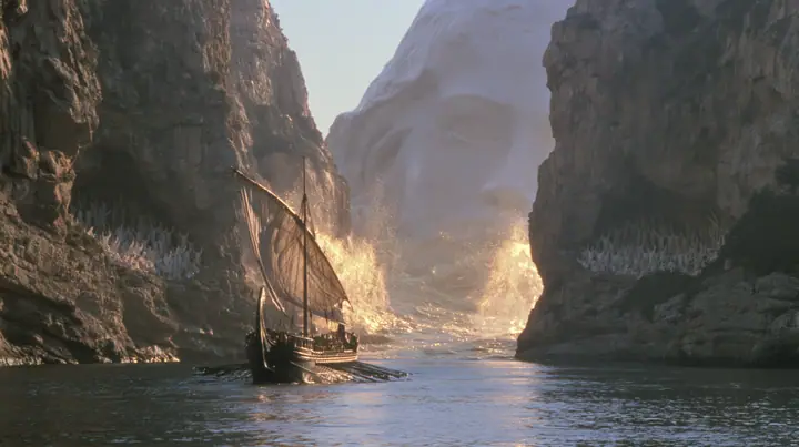extreme wide shot of a long black ancient Greek galley with a single mast, a square sail and two banks of oars passing between the last lit cliffs of a narrow strait, thousands of women in white raising their arms in…
