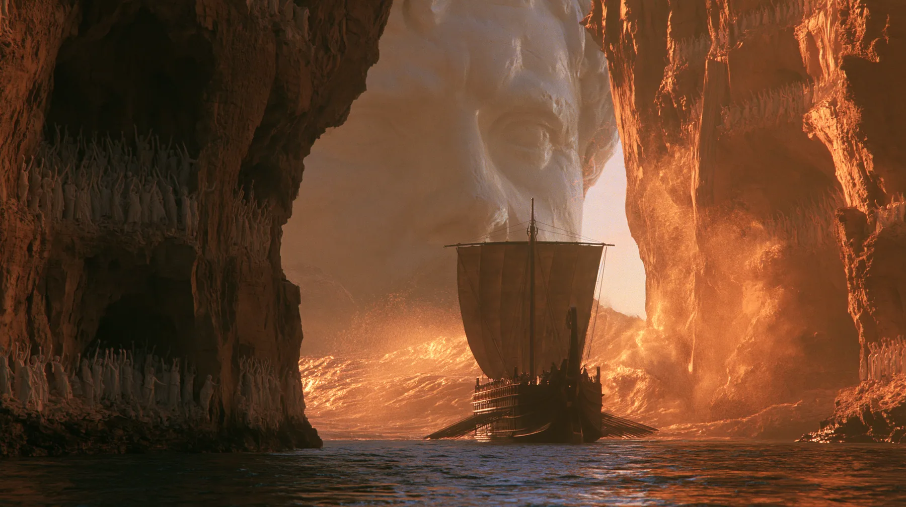 extreme wide shot of a long black ancient Greek galley with a single mast, a square sail and two banks of oars passing between the last lit cliffs of a narrow strait, thousands of women in white raising their arms in…