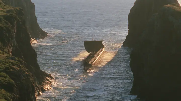 aerial of a long black ancient Greek galley with a single mast, a square sail and two banks of oars leaving a narrow strait of cliffs for the open sea, sunrise, warm gold light and long shadows, spray lit gold,…