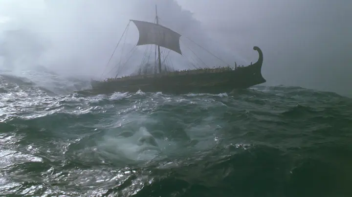 wide shot of a long black ancient Greek galley with a single mast, a square sail and two banks of oars lifted high on a rising mountain of water, and through the translucent face of the swell a colossal pale woman's…