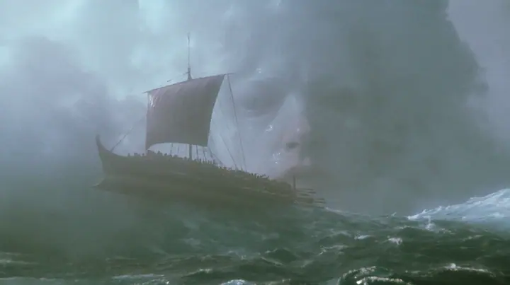 wide shot of a long black ancient Greek galley with a single mast, a square sail and two banks of oars lifted high on a rising mountain of water, and through the translucent face of the swell a colossal pale woman's…