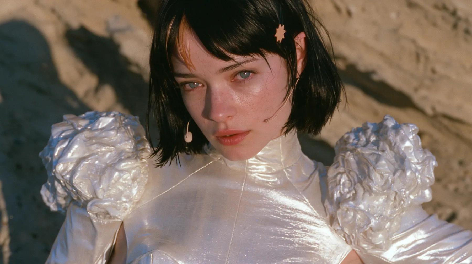 medium shot of a Caucasian American woman in her mid-twenties with pale skin and light freckles, a glossy black blunt jaw-length bob with heavy straight bangs and one clay-orange streak through the bangs, a small…