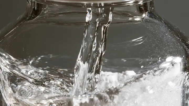 macro of water running down the inside of a small glass vial onto white powder, swirling, macro product photograph, hard rim light, razor-thin focus, no text, no letters, no logos