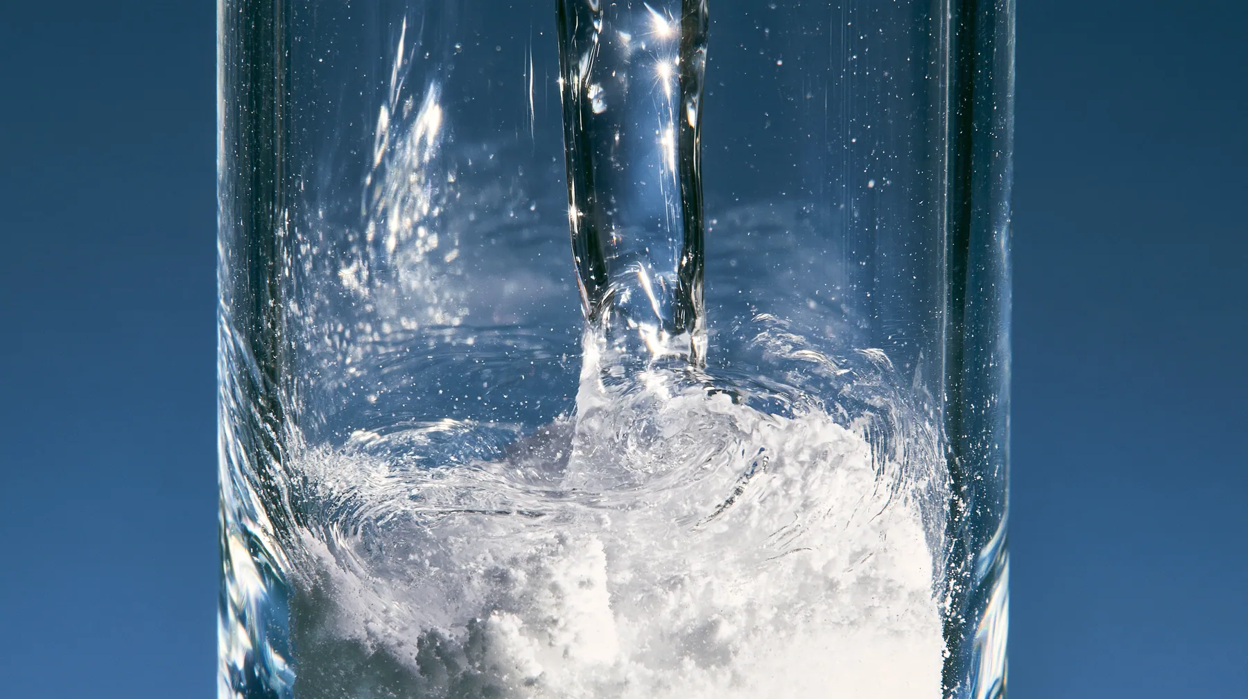 macro of water running down the inside of a small glass vial onto white powder, swirling, macro product photograph, hard rim light, razor-thin focus, no text, no letters, no logos