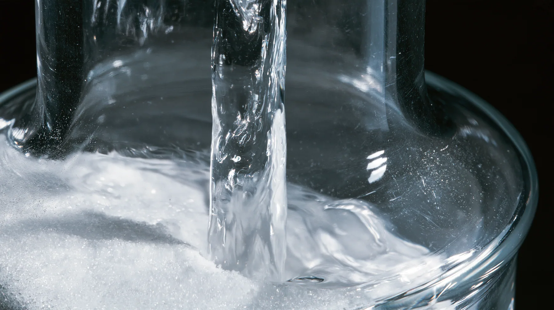 macro of water running down the inside of a small glass vial onto white powder, swirling, macro product photograph, hard rim light, razor-thin focus, no text, no letters, no logos