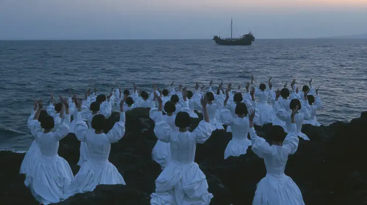 wide shot of hundreds of identical bare-headed women with glossy black bobs in structured white couture gowns on black sea rocks, all raising their arms toward a passing black galley, open ancient sea to the horizon…