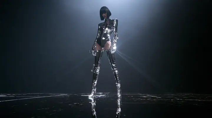 full-body fashion editorial photograph taken from far away with a long lens: a young Caucasian American woman with pale skin and a glossy black blunt bob with heavy straight bangs and one clay-orange streak, in a…