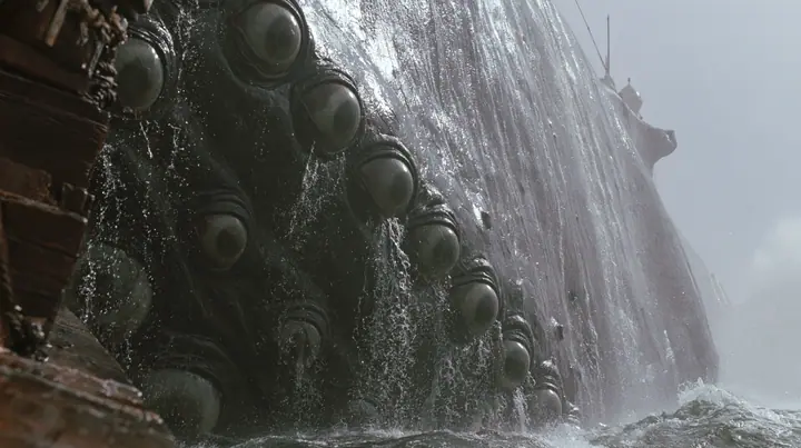 close shot along the flank of a gigantic sea creature breaching beside a wooden galley, its glistening dark skin covered in rows of enormous wet eyes with pale irises, the eyes opening one after another, water…