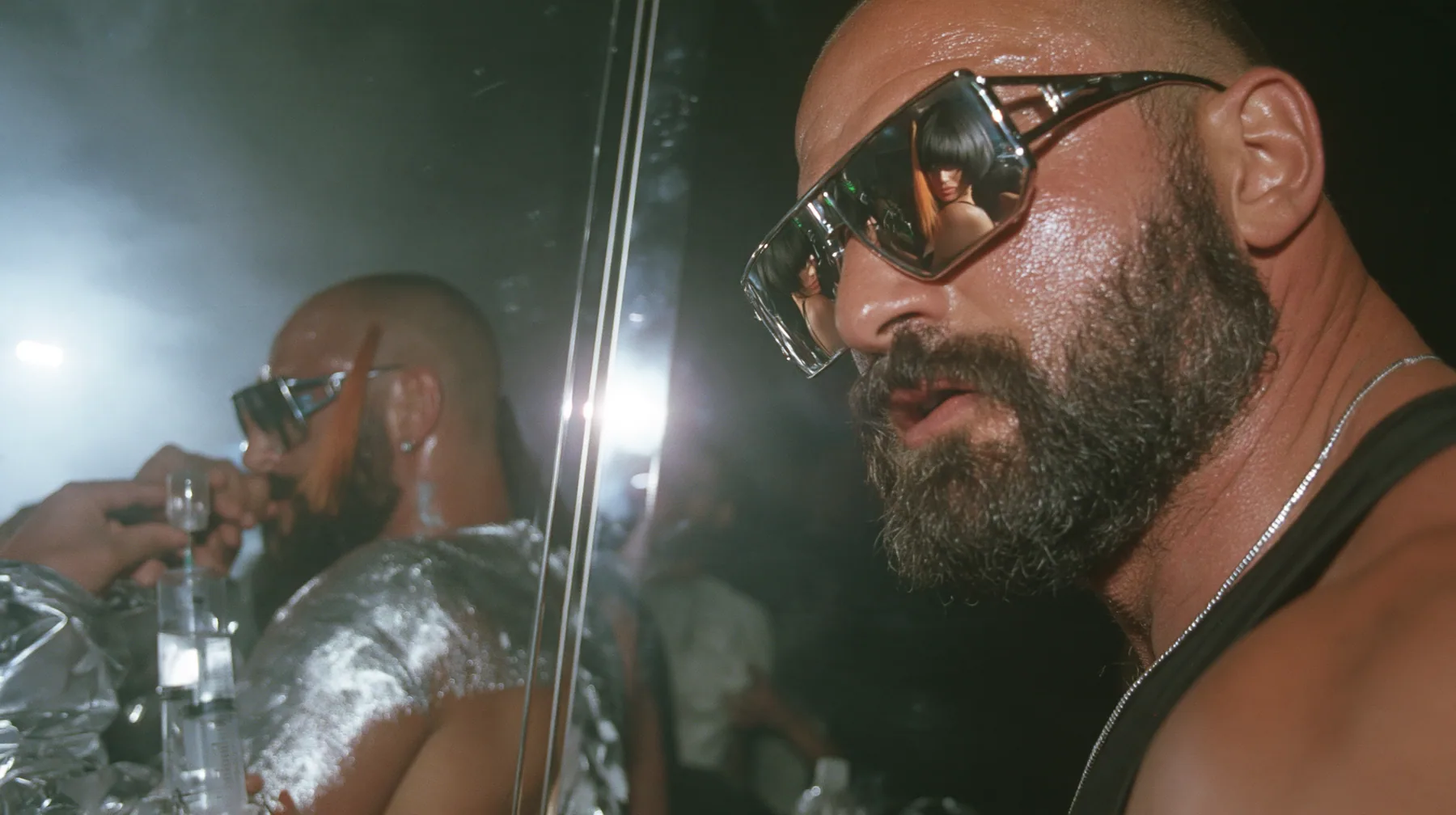 medium shot at a mirrored chrome bar in a warehouse rave, a broad-shouldered Caucasian man in his early thirties with a shaved head, a thick short dark beard, a square jaw, heavy brows and pale blue eyes, the build…
