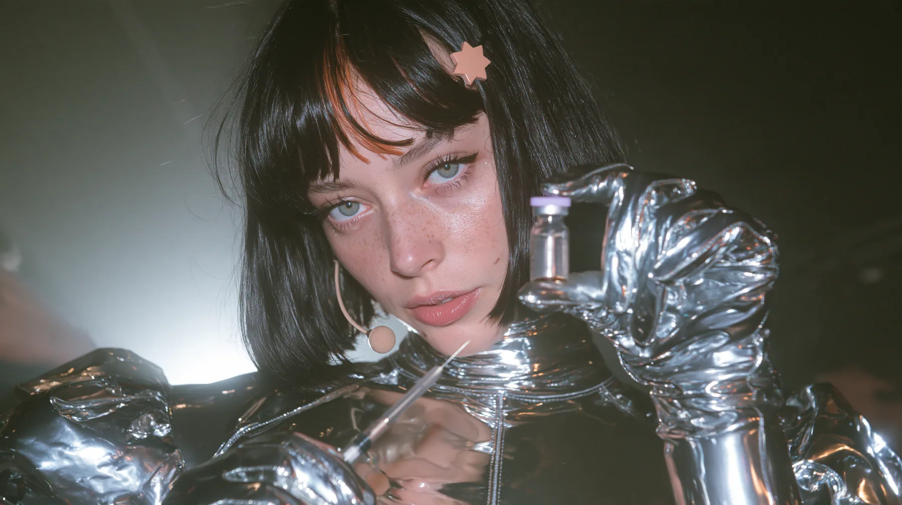 a Caucasian American woman in her mid-twenties with pale skin and light freckles, a glossy black blunt jaw-length bob with heavy straight bangs and one clay-orange streak through the bangs, a small flat clay-orange…