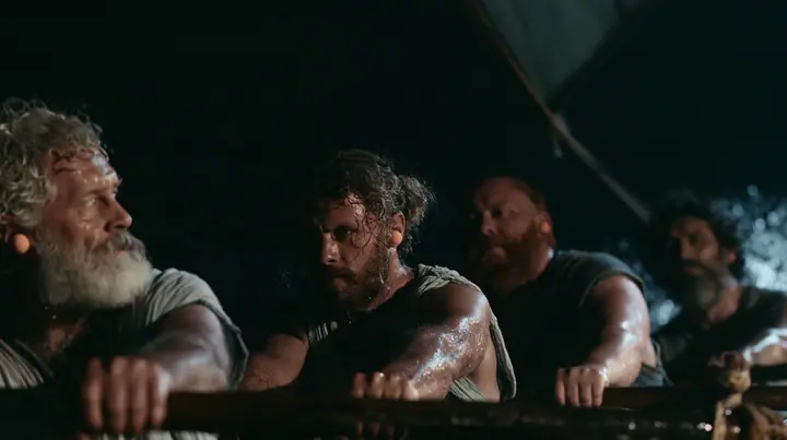medium shot along a rowing bench of a long black ancient Greek galley with a single mast, a square sail and two banks of oars at night, four oarsmen of different ages and builds pulling their oars together, a…