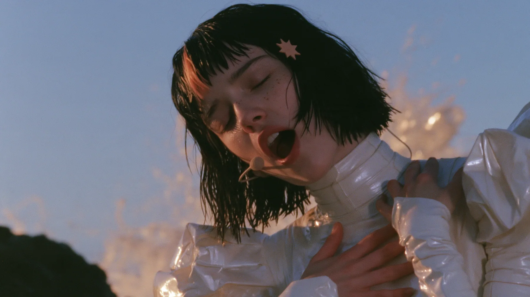medium close-up of a Caucasian American woman in her mid-twenties with pale skin and light freckles, a glossy black blunt jaw-length bob with heavy straight bangs and one clay-orange streak through the bangs, a small…