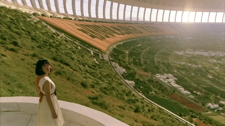 Make this a vast wide 35 mm photograph inside a rotating space colony at morning: keep this woman, a Caucasian American woman in her late twenties with pale skin and a glossy black blunt bob with heavy straight bangs…