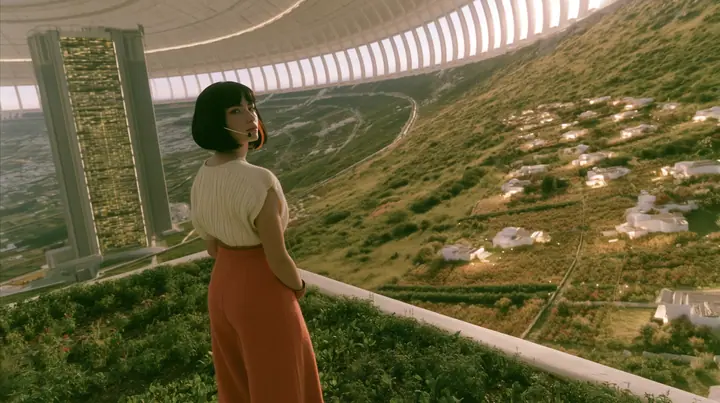 Make this a 35 mm photograph at dusk inside a space colony: on the left third a grey 1970s office tower with lit windows; on the right warm gardens and small white homes glowing; keep this woman, a Caucasian American…