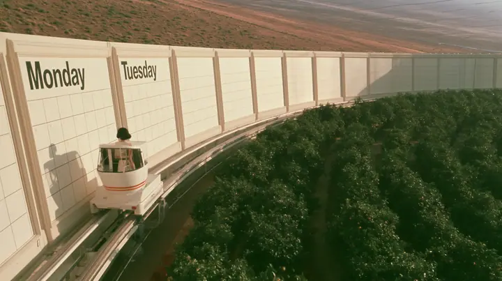Make this a 35 mm photograph from a small open white tram passing through orchards inside a space colony: beside the track a long wall of giant cream calendar pages, the first two carry the words for Monday and…
