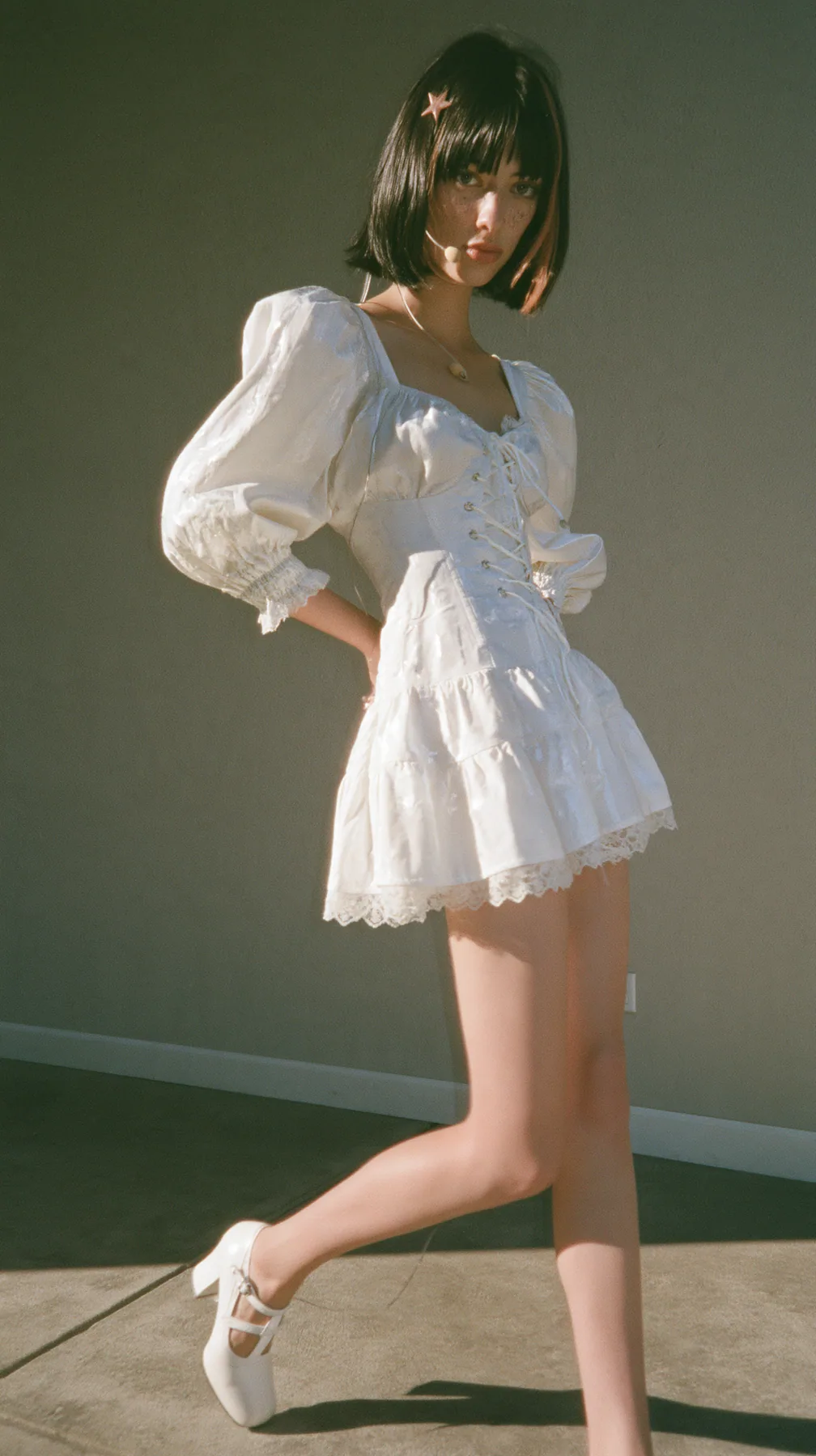 full-length editorial photo, three-quarter view, mid-stride, a 30-year-old Caucasian American woman with a grown-up angular face, pale skin and light freckles, a glossy black blunt bob with heavy straight bangs and…