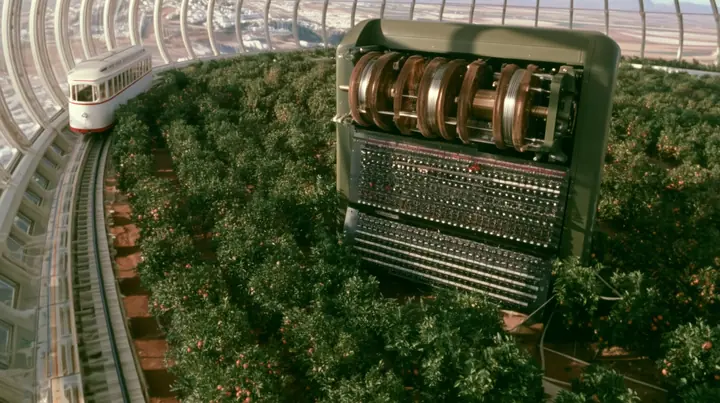 Make this the same photograph with nobody in it: remove the woman and continue the scene behind her where she stood. Keep everything else exactly: the giant Enigma machine, the orchard and the white tram on its rail,…
