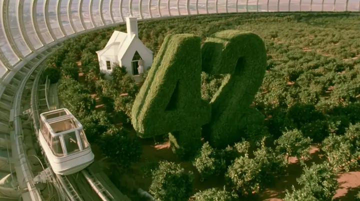 Make this the same photograph with nobody in it: remove the woman and continue the scene behind her where she stood. Keep everything else exactly: the hedges clipped into the number 42, the little white chapel and…