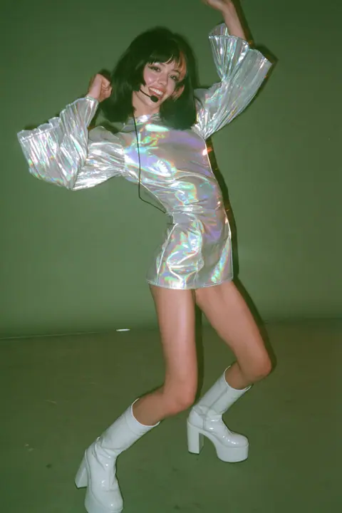 Y2K high fashion editorial, a 2001 couture magazine story: full-length shot, head to toe with the feet in frame, of a young Caucasian American woman with pale skin and a glossy black blunt bob with heavy straight…