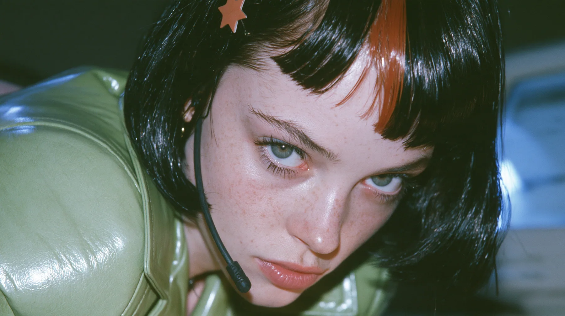 Y2K high fashion editorial, a 2001 couture magazine story: medium close-up of a Caucasian American woman in her mid-twenties with pale skin and light freckles, a glossy black blunt jaw-length bob with heavy straight…