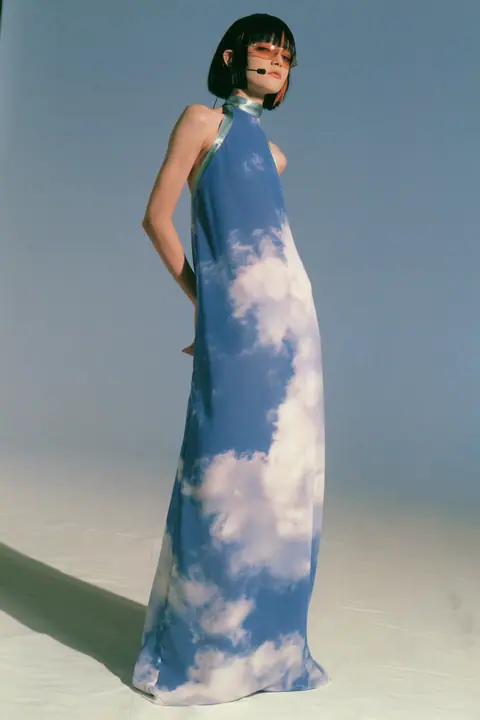 Y2K high fashion editorial, a 2001 couture magazine story: full-length shot, head to toe with the feet in frame, of a young Caucasian American woman with pale skin and a glossy black blunt bob with heavy straight…