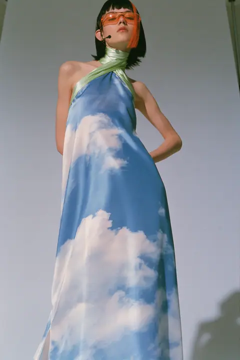 Y2K high fashion editorial, a 2001 couture magazine story: full-length shot, head to toe with the feet in frame, of a young Caucasian American woman with pale skin and a glossy black blunt bob with heavy straight…