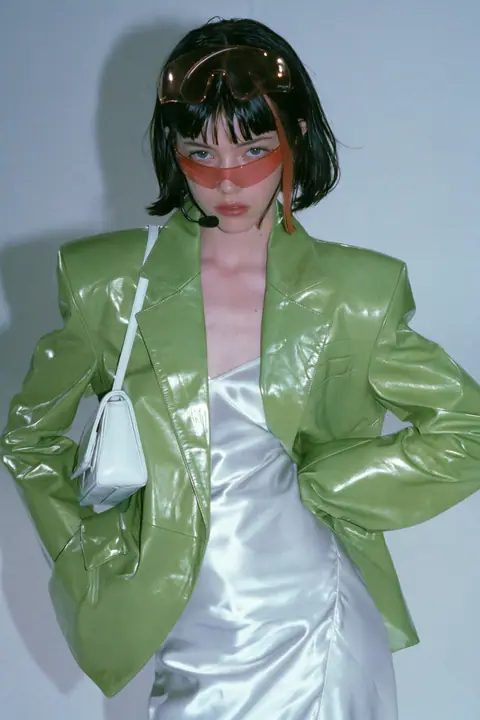 Y2K high fashion editorial, a 2001 couture magazine story: full-length shot, head to toe with the feet in frame, of a young Caucasian American woman with pale skin and a glossy black blunt bob with heavy straight…