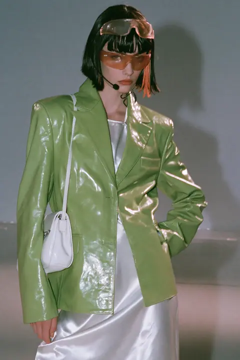 Y2K high fashion editorial, a 2001 couture magazine story: full-length shot, head to toe with the feet in frame, of a young Caucasian American woman with pale skin and a glossy black blunt bob with heavy straight…