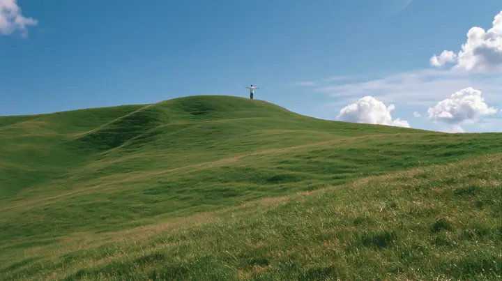 Y2K high fashion editorial photograph, 2001: a vast wide shot of a smooth rolling bright-green grassy hill with soft curves, the grass short and velvety with a tiny lone figure standing on the crest seen from behind,…