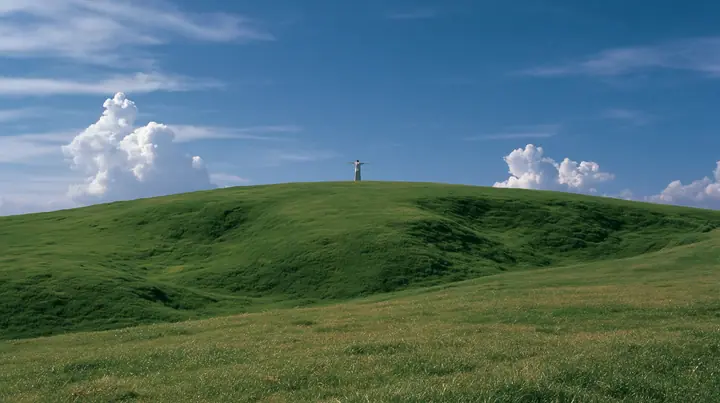 Y2K high fashion editorial photograph, 2001: a vast wide shot of a smooth rolling bright-green grassy hill with soft curves, the grass short and velvety with a tiny lone figure standing on the crest seen from behind,…