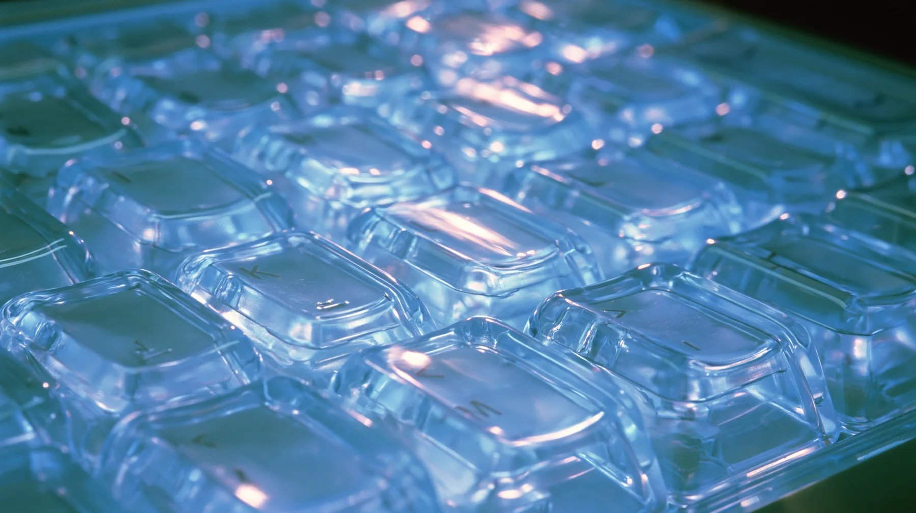 Y2K high fashion editorial photograph, 2001: a luxury product macro of a translucent ice-blue keyboard from 2001, its keys glowing softly, shallow depth of field, no text, no letters, no logos