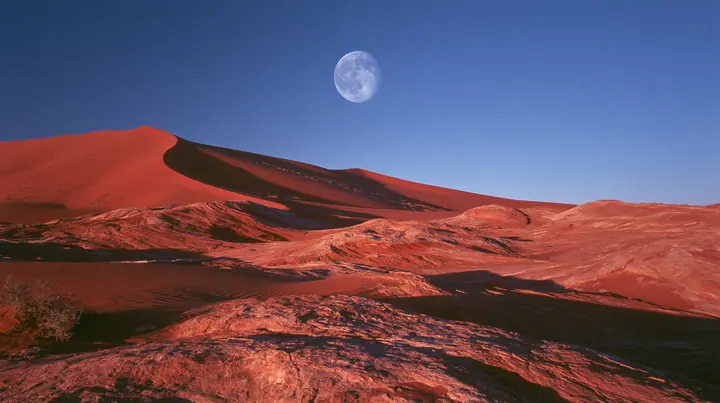 Y2K high fashion editorial photograph, 2001: a luxury campaign landscape of red sandstone dunes under a deep blue dusk sky with a pale full moon, medium-format slide film, no text, no letters, no logos