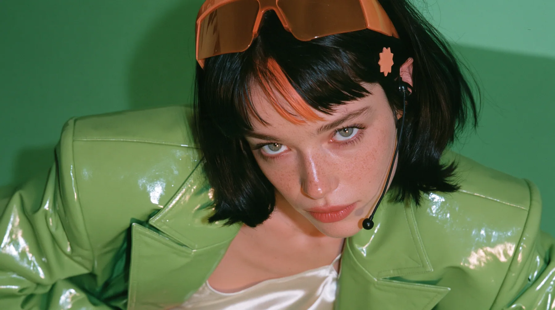 Y2K high fashion editorial, 2001: a medium close-up of a Caucasian American woman in her mid-twenties with pale skin and light freckles, a glossy black blunt jaw-length bob with heavy straight bangs and one…