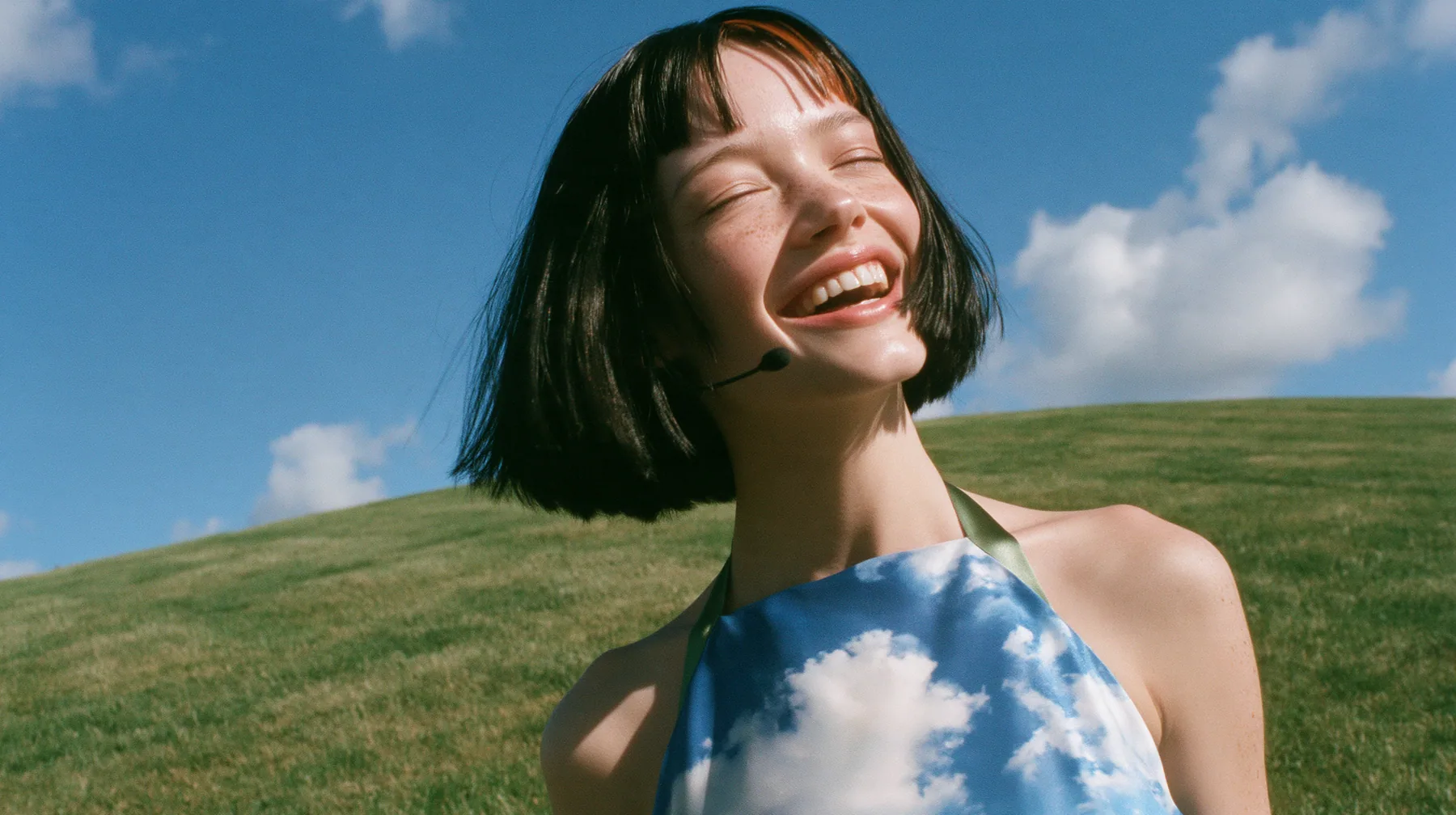 Y2K high fashion editorial, 2001: a medium shot of a Caucasian American woman in her mid-twenties with pale skin and light freckles, a glossy black blunt jaw-length bob with heavy straight bangs and one clay-orange…