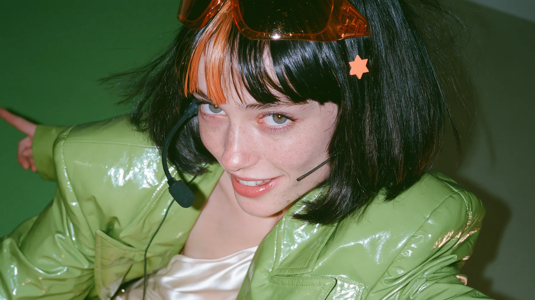 Y2K high fashion editorial, a 2001 couture magazine story: a medium shot of a Caucasian American woman in her mid-twenties with pale skin and light freckles, a glossy black blunt jaw-length bob with heavy straight…