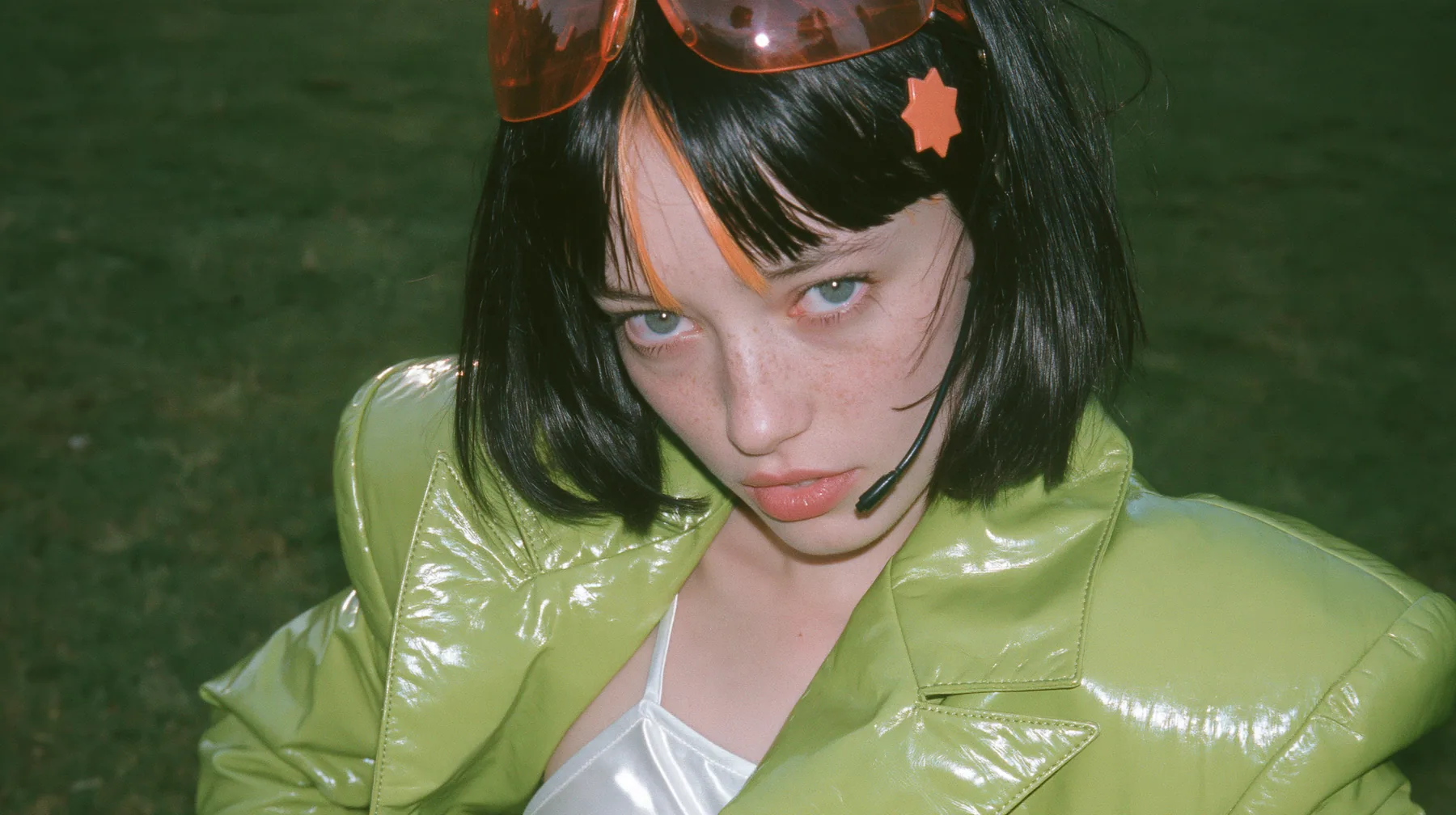 Y2K high fashion editorial, a 2001 couture magazine story: a medium shot of a Caucasian American woman in her mid-twenties with pale skin and light freckles, a glossy black blunt jaw-length bob with heavy straight…