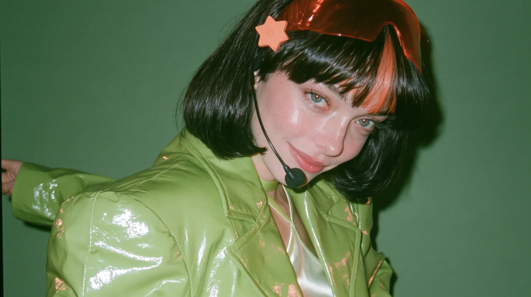 Y2K high fashion editorial, a 2001 couture magazine story: a medium shot of a Caucasian American woman in her mid-twenties with pale skin and light freckles, a glossy black blunt jaw-length bob with heavy straight…