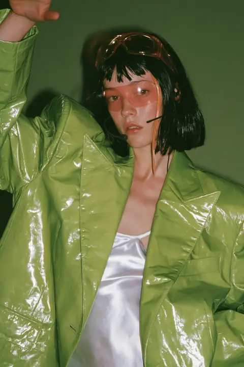 Y2K high fashion editorial, a 2001 couture magazine story: full-length shot, head to toe with the feet in frame, of a young Caucasian American woman with pale skin and a glossy black blunt bob with heavy straight…