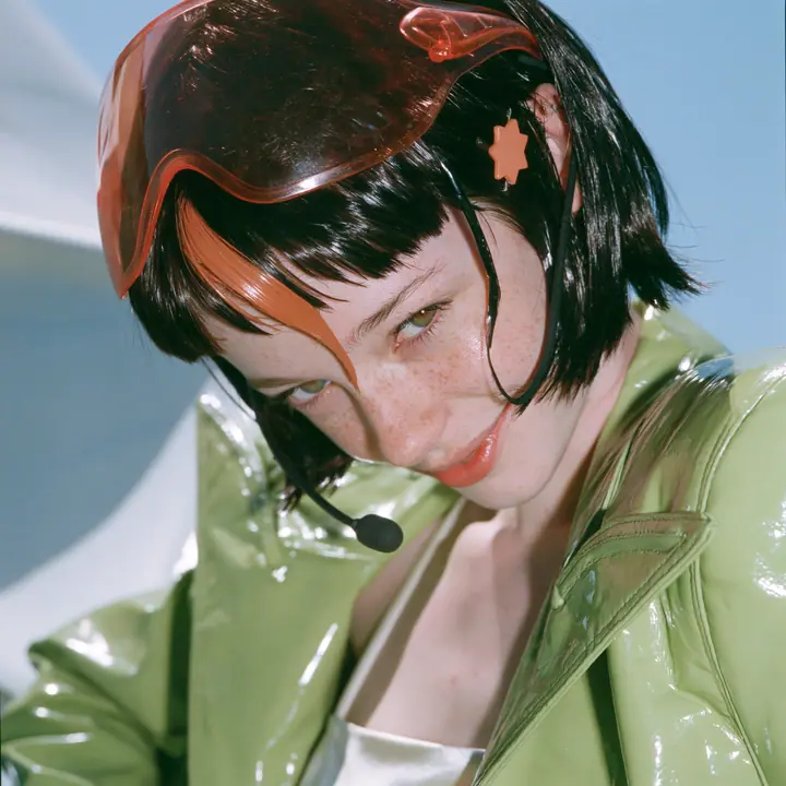 Y2K high fashion editorial, a 2001 couture magazine story: a square beauty portrait of a Caucasian American woman in her mid-twenties with pale skin and light freckles, a glossy black blunt jaw-length bob with heavy…