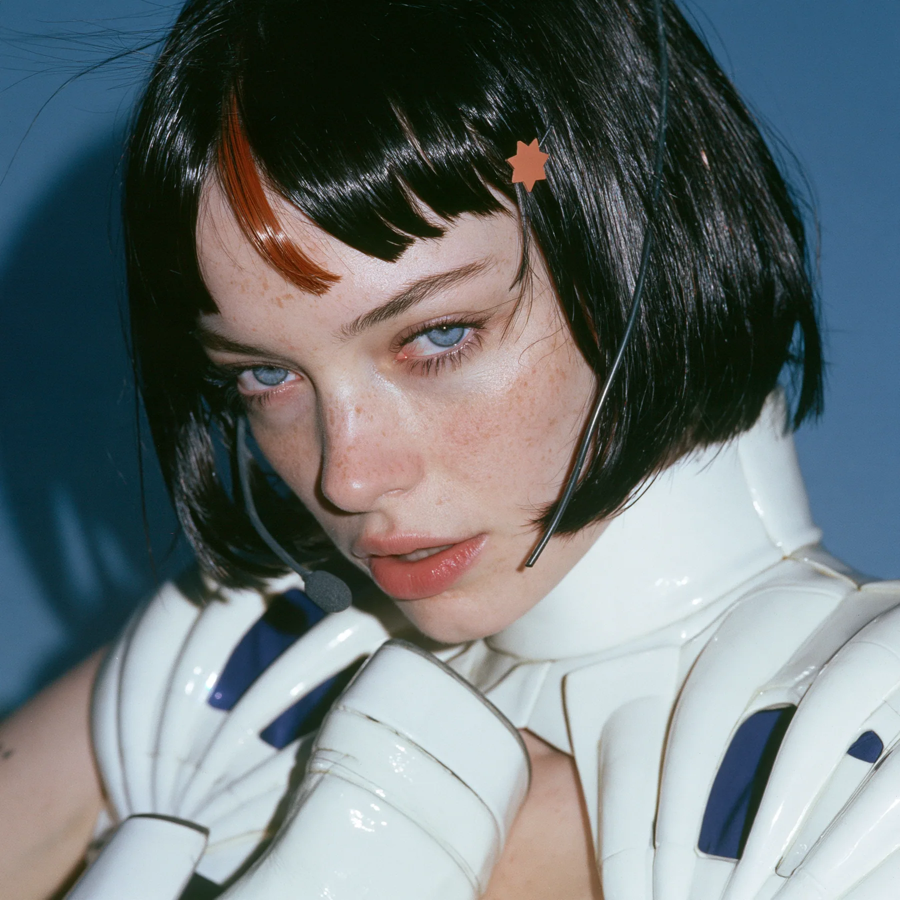 Y2K high fashion editorial, a 2001 couture magazine story: a square beauty portrait of a Caucasian American woman in her mid-twenties with pale skin and light freckles, a glossy black blunt jaw-length bob with heavy…