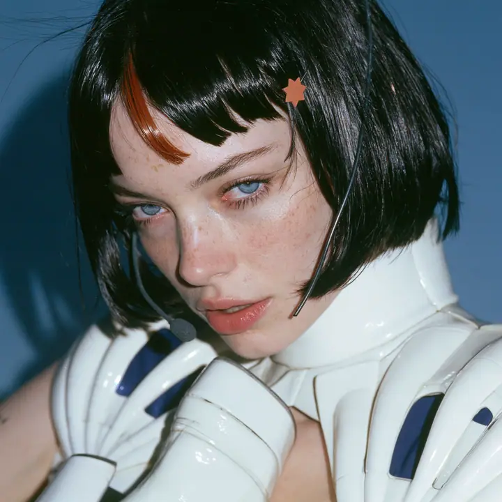 Y2K high fashion editorial, a 2001 couture magazine story: a square beauty portrait of a Caucasian American woman in her mid-twenties with pale skin and light freckles, a glossy black blunt jaw-length bob with heavy…